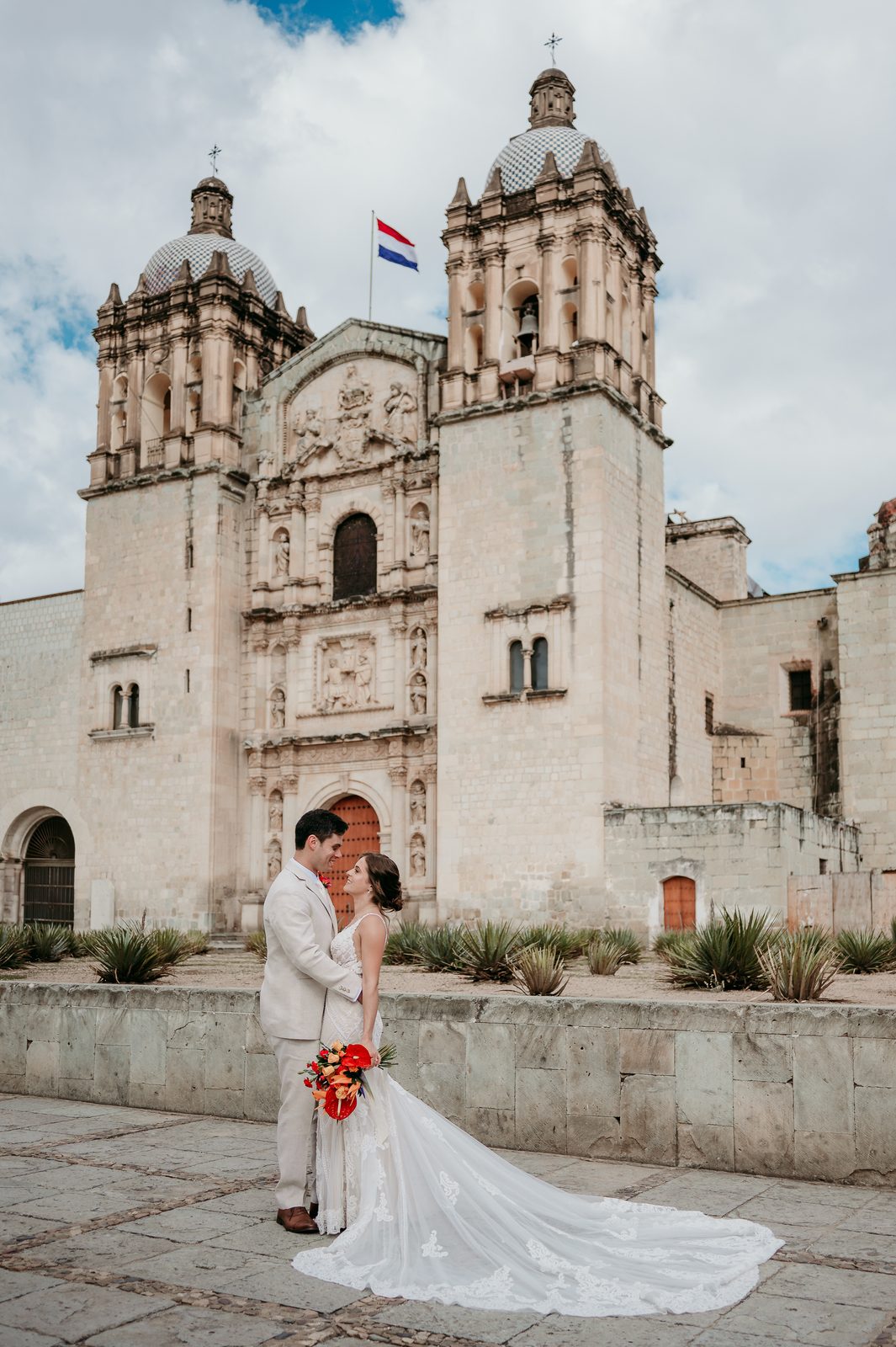 Aron and Rebecca on their wedding day in front of a historic stone church.